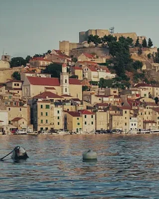 A stone harbour town on a hillside above calm water