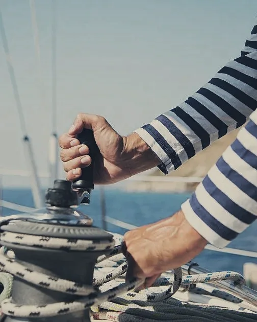 Hands working a winch on a sailing yacht